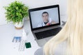 A woman communicates via a computer with a doctor via video link. Medical assistance under quarantine conditions. Remote consultat