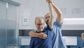 Medical assistant raising arms of elder person to stretch muscles