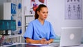 Medical assistant typing on laptop and taking notes on clipboard Royalty Free Stock Photo