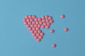 Medical background or banner. Pink Pills in form of broke heart on blue background. Flat lay