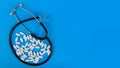 Medical background. Stethoscope and pills on a blue background.