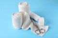 Medical bandage rolls, sticking plaster and scissors on light blue background Royalty Free Stock Photo