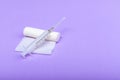 Medical bandage and syringe on a lilac background. A gauze roll on which the syringe lies. Dressing for medical purposes. Space Royalty Free Stock Photo