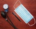 medical blue mask with pen and manual blood pressure reader with wood background representing work of doctors Royalty Free Stock Photo