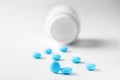 Medical blue pills and white bottle on white light background. Concept of healthcare and medicine. Royalty Free Stock Photo