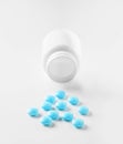 Medical blue pills and white bottle on white light background. Concept of healthcare and medicine. Royalty Free Stock Photo