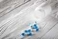 Medical blue pills and white bottle on white wooden background. Royalty Free Stock Photo