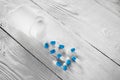 Medical blue pills and white bottle on white wooden background. Royalty Free Stock Photo