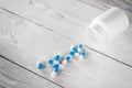 Medical blue pills and white bottle on wooden background. Royalty Free Stock Photo