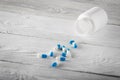 Medical blue pills and white bottle on wooden background. Royalty Free Stock Photo