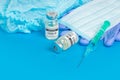 Medical bottle vials syringes and face mask on blue background with copy space. Vaccination session and immunity improvement