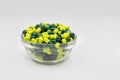 Medical capsules yellow green in glass bowl closeup against white