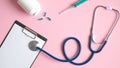 Medical checkup concept. Medical equipment on pink background. Top view doctors table with stethoscope, medical clipboard, syringe
