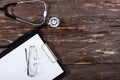 Medical clipboard and stethoscope on dark wooden table. Royalty Free Stock Photo