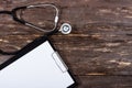 Medical clipboard and stethoscope on dark wooden table. Royalty Free Stock Photo