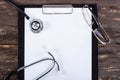 Medical clipboard and stethoscope on dark wooden table. Royalty Free Stock Photo