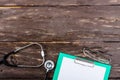 Medical clipboard and stethoscope on dark wooden table. Royalty Free Stock Photo