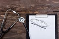 Medical clipboard and stethoscope on old dark wooden table Royalty Free Stock Photo
