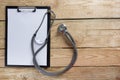 Medical clipboard and stethoscope on wooden desk background. Top view. Workplace of a doctor. Royalty Free Stock Photo