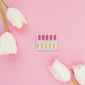 Medical composition with vitamins pills and white flowers on pink background. Flat lay, top view. Royalty Free Stock Photo