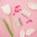 Medical composition with vitamins pills and white flowers on pink background. Flat lay Royalty Free Stock Photo