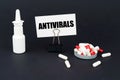 On a black surface are pills, a nasal spray and a paper sign with the inscription - Antivirals Royalty Free Stock Photo