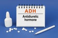 On a blue background, a pen, tablets and a notepad with the inscription - ADH Antidiuretic hormone