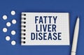 On a blue background, a pen, tablets and a notepad with the inscription - FATTY LIVER DISEASE