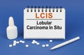 On a blue background, a pen, tablets and a notepad with the inscription - LCIS Lobular Carcinoma In Situ