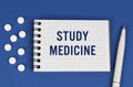 On a blue background, a pen, tablets and a notepad with the inscription - STUDY MEDICINE