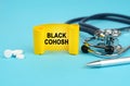 On a blue surface, a stethoscope, pills, a pen and a yellow sign with the inscription - Black Cohosh Royalty Free Stock Photo