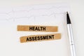 On the cardiogram lies a pen and torn paper with the text - HEALTH ASSESSMENT