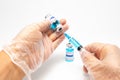 Medical concept - Close-up of hands with surgical glove holding syringe with needle and COVID-19 vaccine vial. Copy space Royalty Free Stock Photo