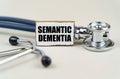 On a gray background, a stethoscope and a cardboard sign with the inscription - Semantic dementia