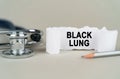 On a gray background, a stethoscope, a pencil and a paper plate with the inscription - Black lung