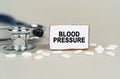 On a gray background, a stethoscope, pills and a cardboard plate with the inscription - Blood pressure Royalty Free Stock Photo