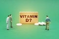 On the green surface are pills, miniature figures of people and a sign with the inscription - Vitamin D