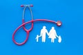 Family doctor desk with stethoscope and paper figures on blue background top view