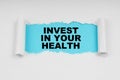 In the middle of a white sheet in space on a blue background the inscription - INVEST IN YOUR HEALTH Royalty Free Stock Photo