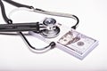 Medical concept - stethoscope over the dollar bills isolated on white background. Royalty Free Stock Photo
