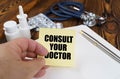 The doctor is holding a sticker with the inscription - Consult your doctor