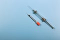 Medical concept. Two syringes for injections on a blue background. Insulin and retro iron syringe