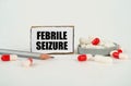 On a white background, medical capsules, a pencil and a cardboard plate with the inscription - FEBRILE SEIZURE Royalty Free Stock Photo