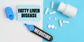 On the white and blue surface are pills, a marker and paper with the inscription - FATTY LIVER DISEASE Royalty Free Stock Photo