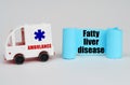 On a white surface, an ambulance and a blue paper sign with the inscription - Fatty liver disease Royalty Free Stock Photo