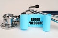 On a white surface lies a stethoscope and a blue roll of paper with the inscription - Blood Pressure Royalty Free Stock Photo