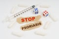 On a white surface lies a syringe, pills, dice and pieces of paper with the inscription - STOP PSORIASIS Royalty Free Stock Photo