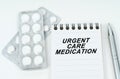 On a white surface are pills in a package, a pen and a notepad with the inscription - URGENT CARE MEDICATION
