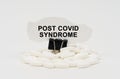 On a white surface are pills and torn paper with the inscription - Post covid syndrome