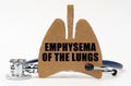 On a white surface are a stethoscope and a cardboard figure of a lung with the inscription - Emphysema of the lungs